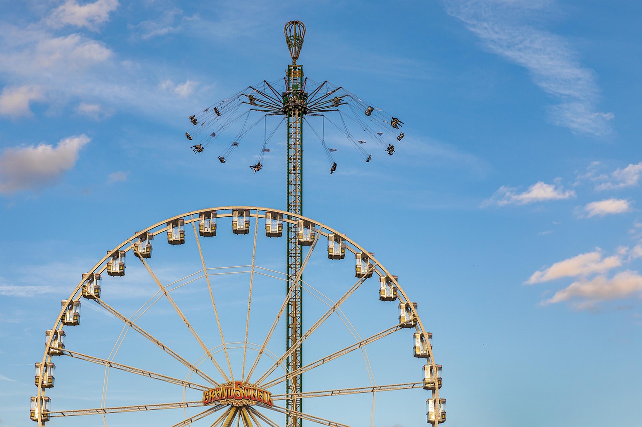 Blue sky with a big wheel and tall swing ride in the background