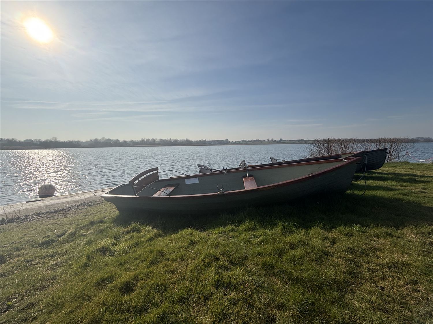 A photo of a rowing boat on the grass next to Hornsea Mere in the sunshine
